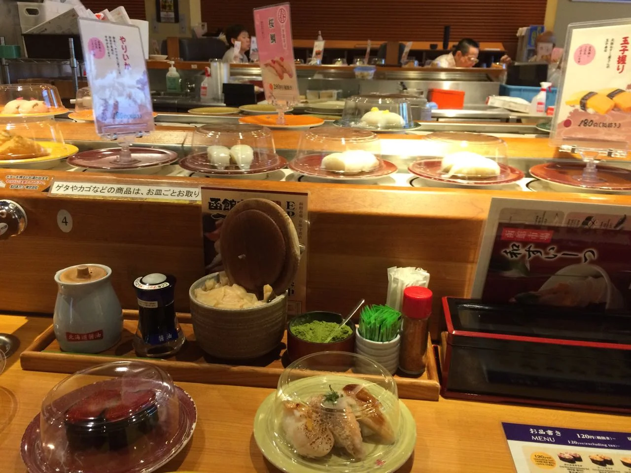 Kaitenzushi (conveyor-belt sushi) near the station. Note the cup of matcha sitting in the row of condiments between the gari ginger and wasabi.