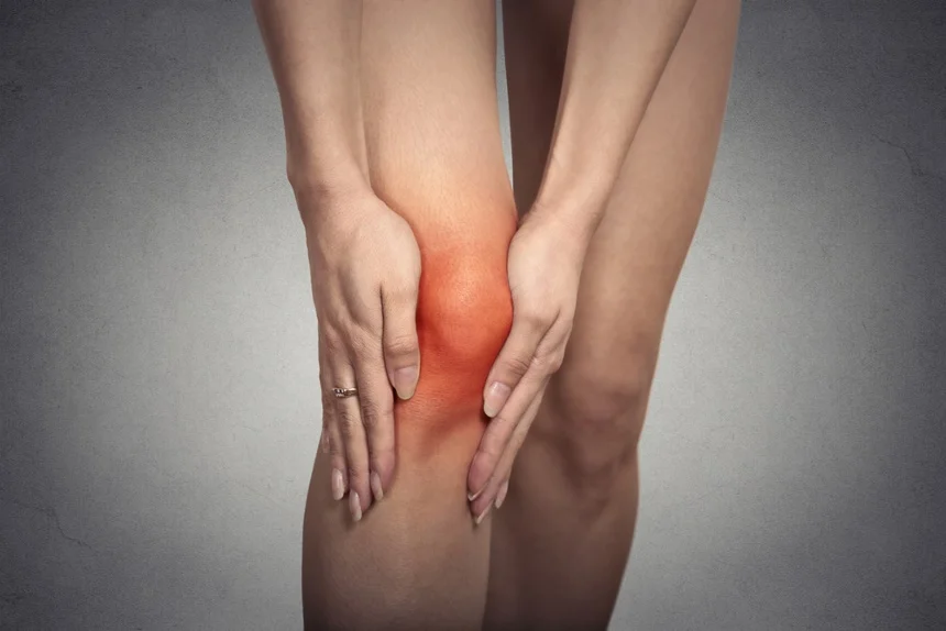 Closeup tendon knee joint problems on woman leg indicated with red spot isolated on gray background. Joint inflammation concept..jpeg