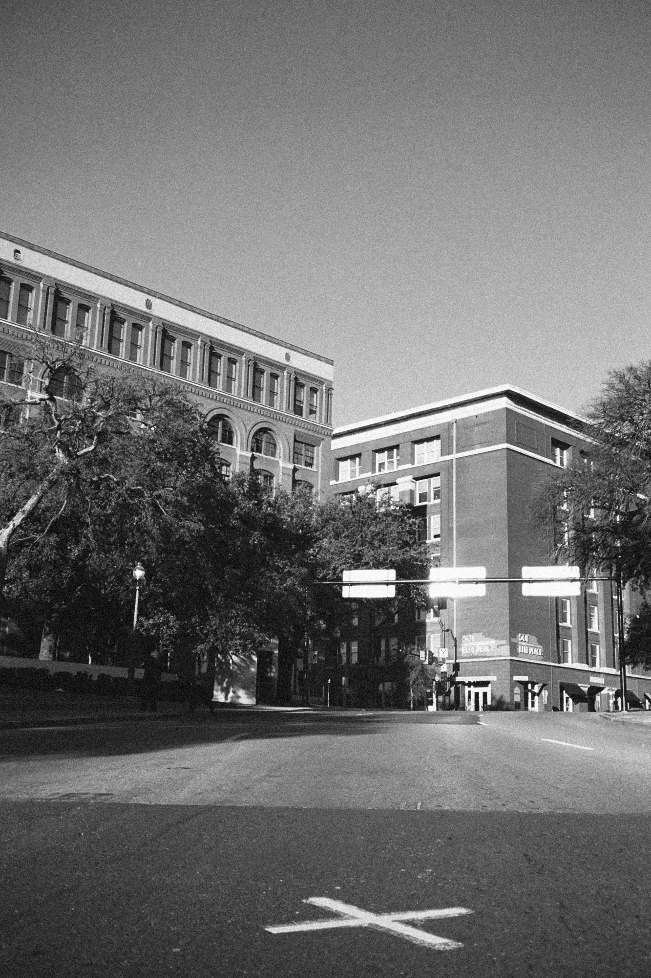 X marks the spot where the first shot hit U.S President John F. Kennedy in a successful assassination attempt on November 22, 1963 with the building where the supposed shooting came from on the background. Dallas, TX. 2014