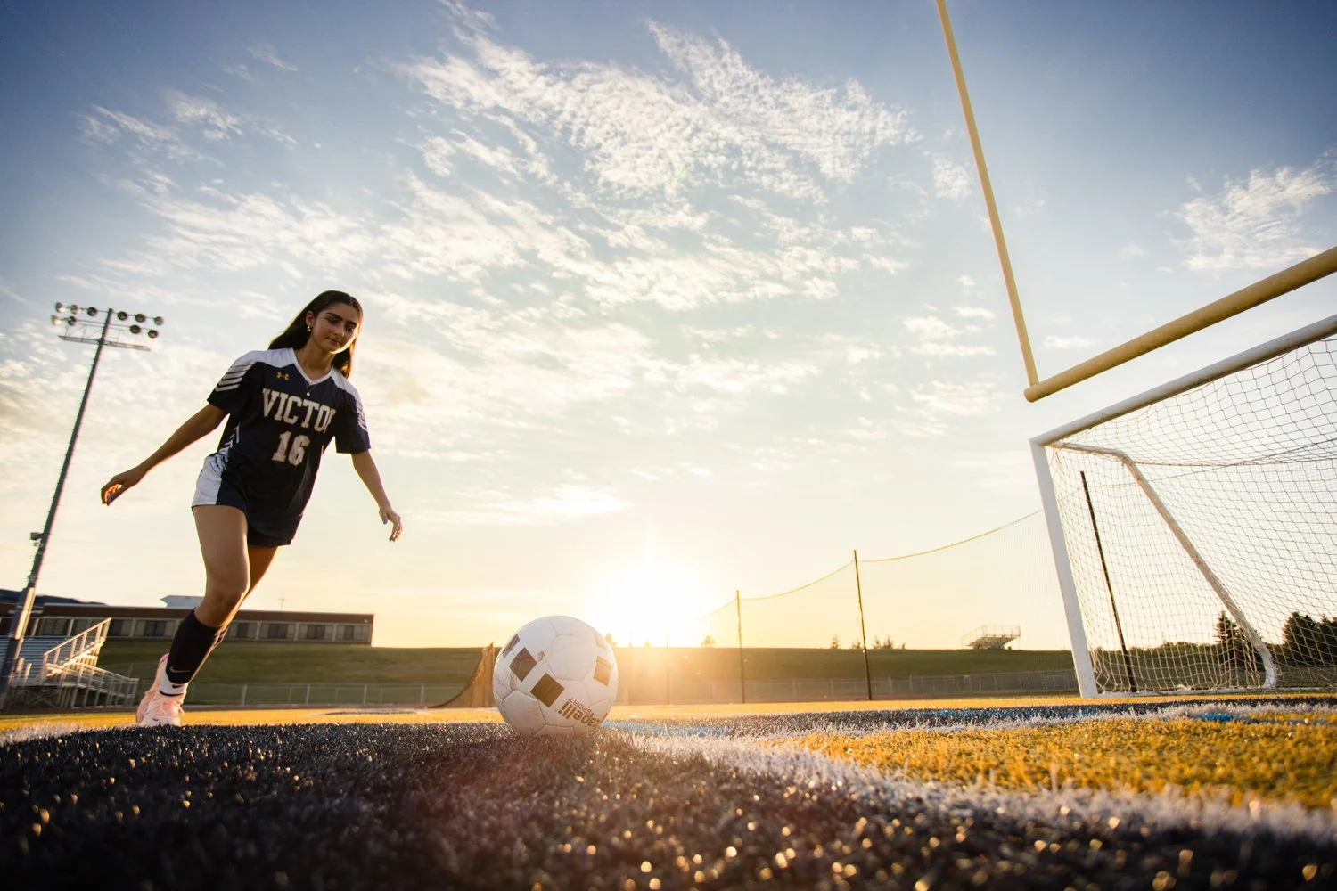High school senior soccer player during Victor NY senior pictures at outdoor field at sunset