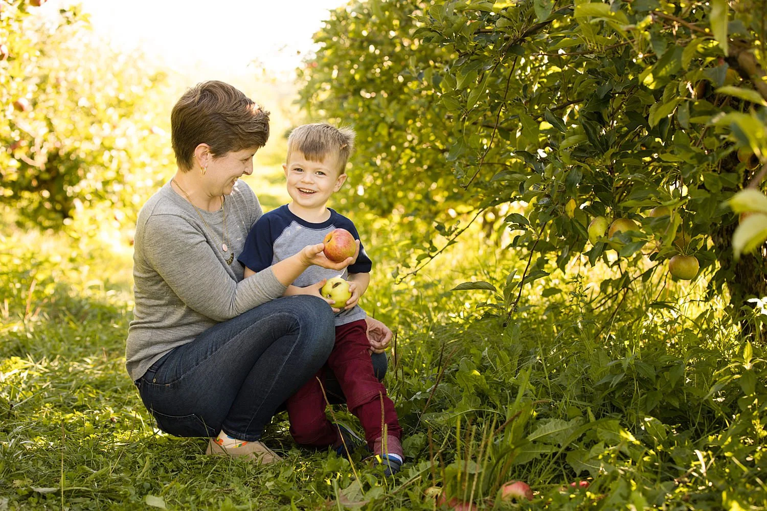 Candid family photo session featuring mother and son smiling during apple picking
