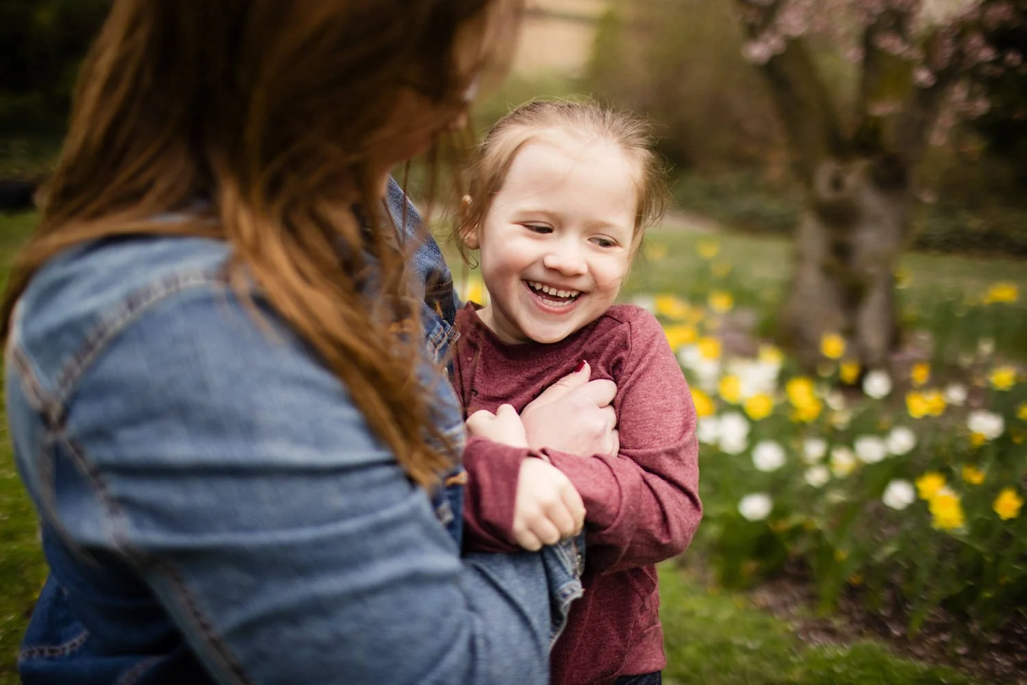 Young girl smiling while being held during family pictures at Eastman Museum in Rochester NY