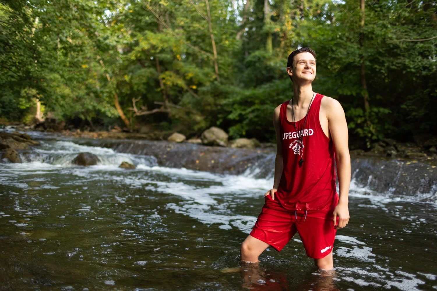 High school senior lifeguard standing in river during Penfield NY senior portraits