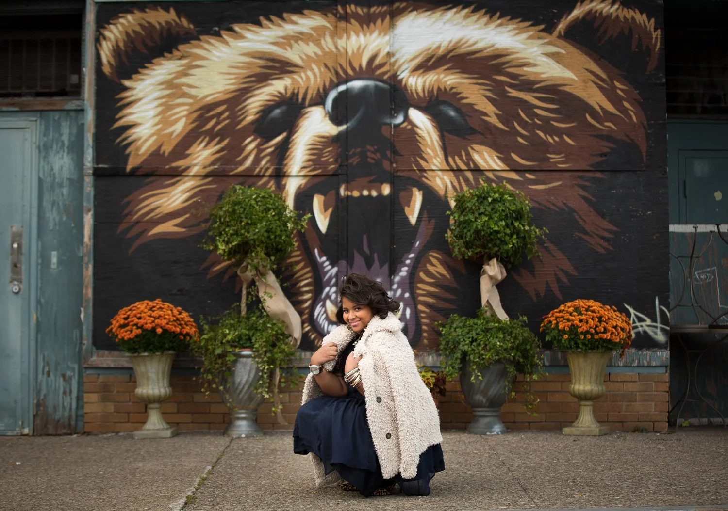 High school senior kneeling in front of mural during Rochester Public Market senior pictures