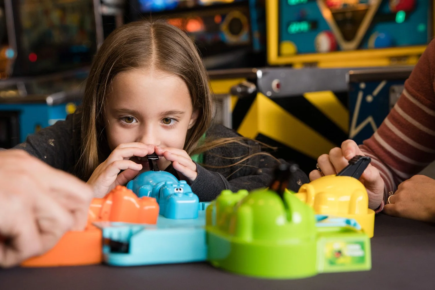 Young girl playing arcade game during candid family pictures in East Rochester NY