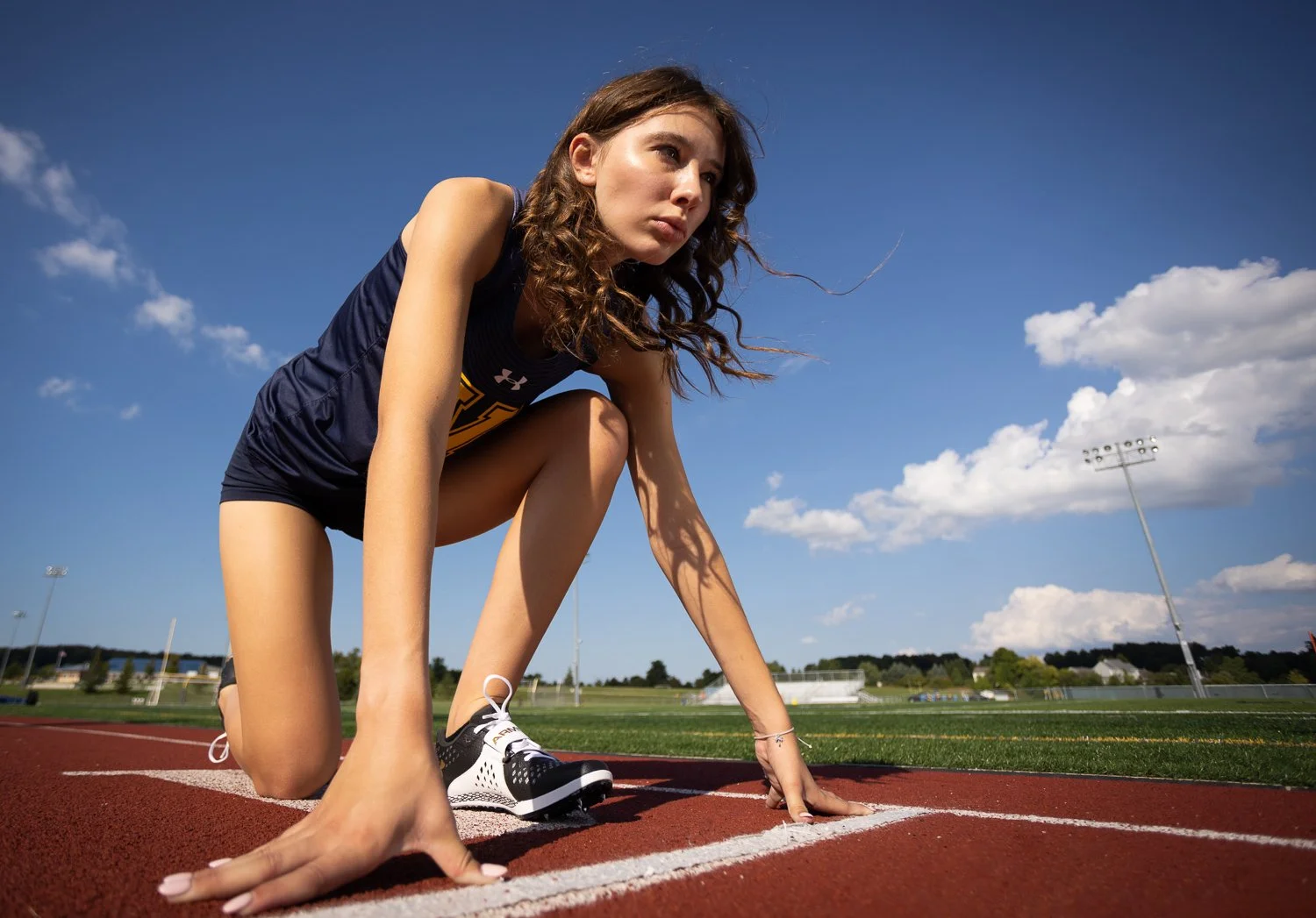 Senior photo session capturing track athlete at starting line on outdoor running track