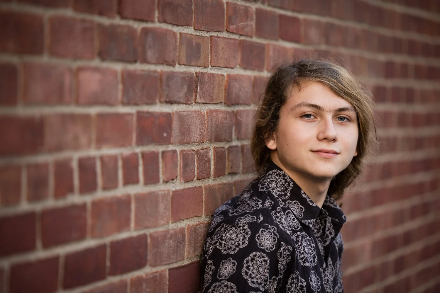 Rochester NY senior picture featuring high school senior leaning against brick wall