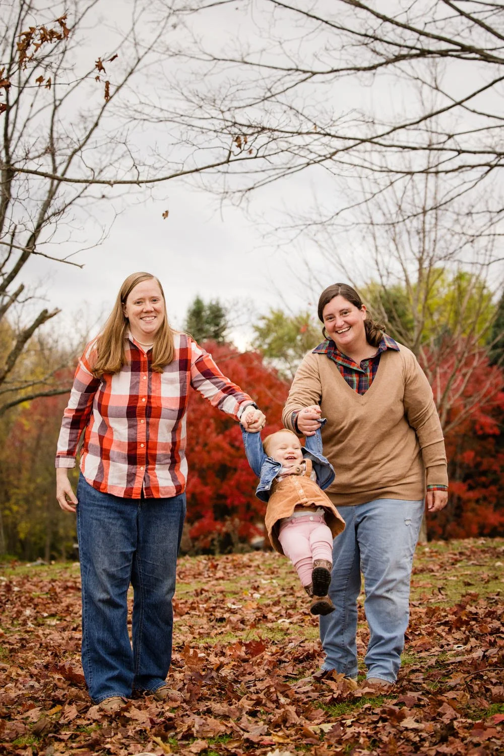 Two moms walking with toddler during fall family pictures at Chase Farms