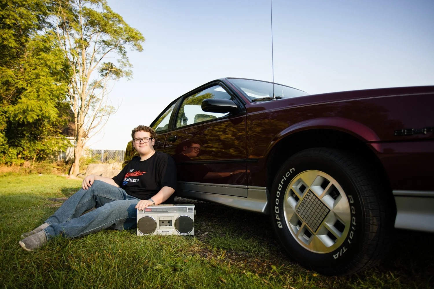 Bishop Kearney High School senior pictures featuring student leaning against vintage car outdoors with a boombox nearby