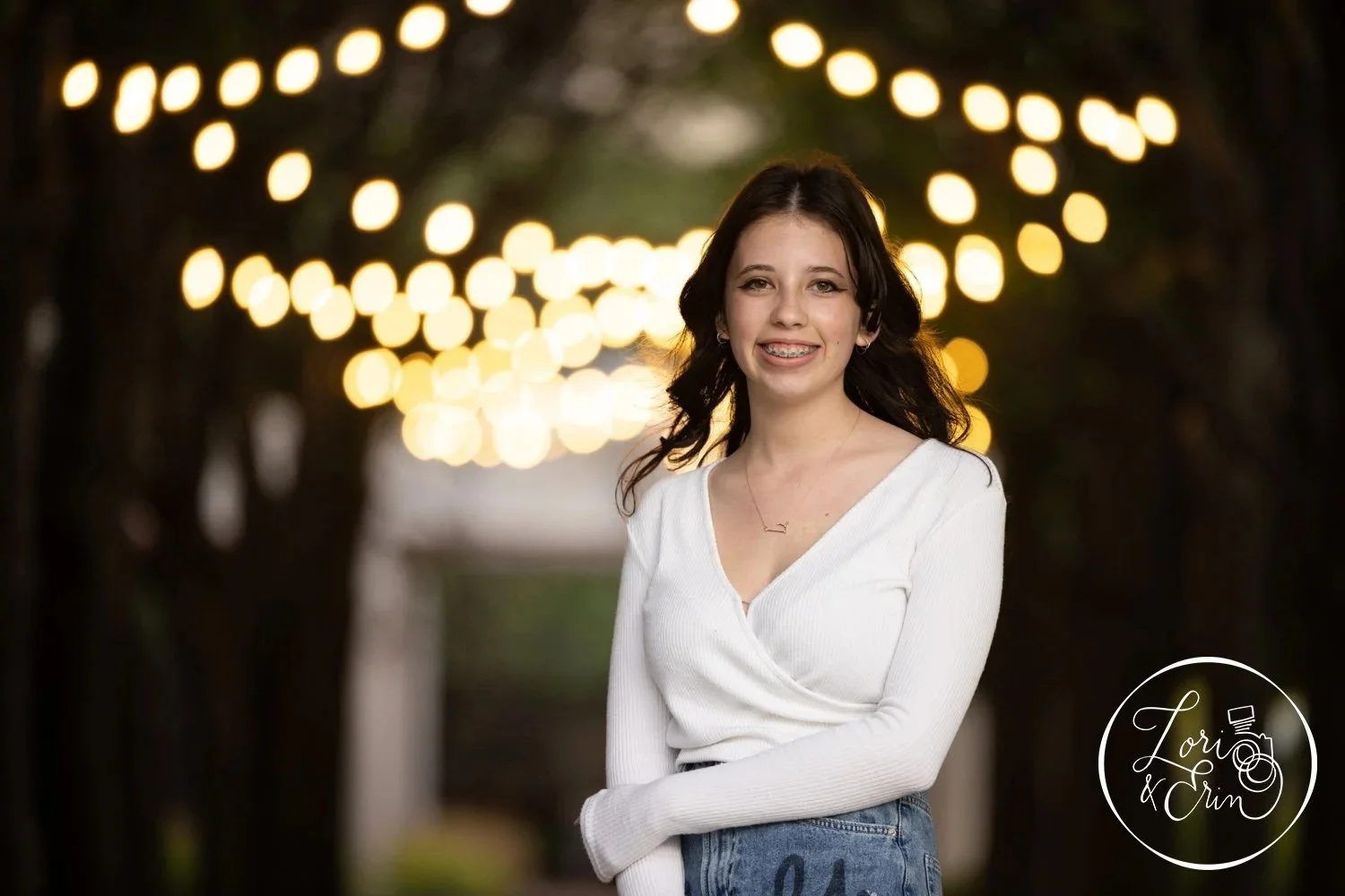 A high school senior girl under a string of lights at her senior pictures at the Memorial Art Gallery