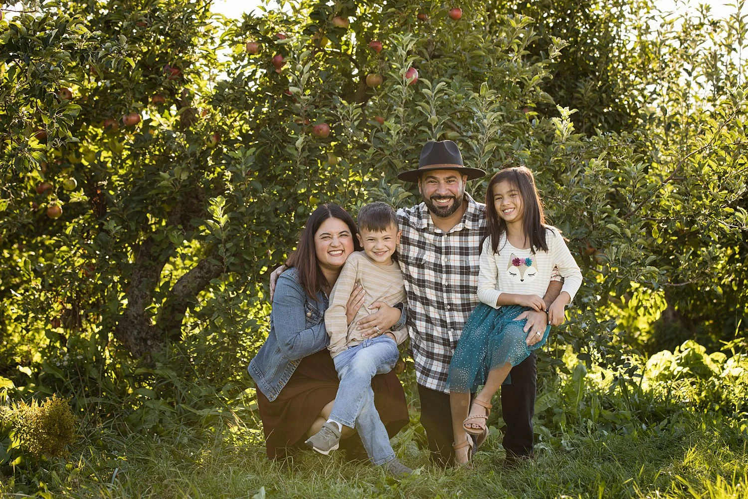 Victor NY family pictures at golden hour featuring family of four in apple orchard