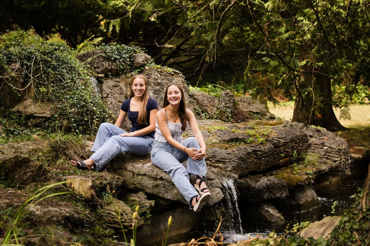 Senior pictures at Sonnenberg Gardens featuring twin girls by waterfall