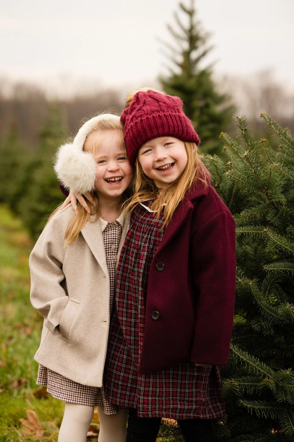 Two girls in winter coats during family pictures at Christmas tree farm