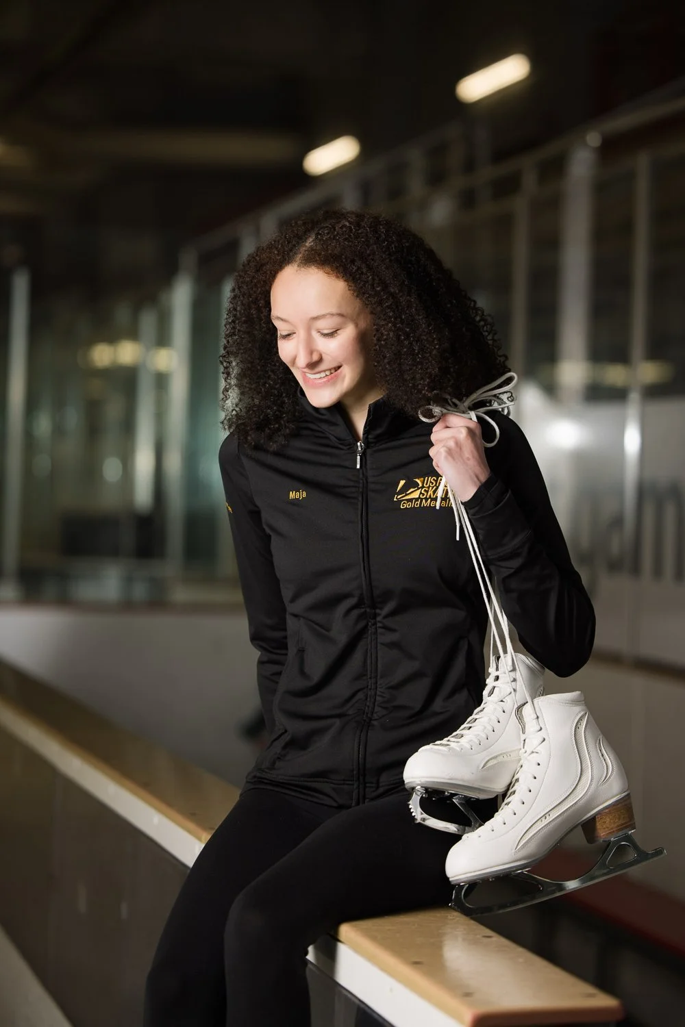 Senior pictures featuring high school senior holding ice skates at rink