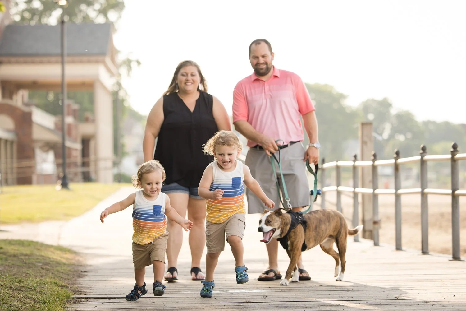 Family pictures at Charlotte in Rochester NY featuring family walking with dog on boardwalk