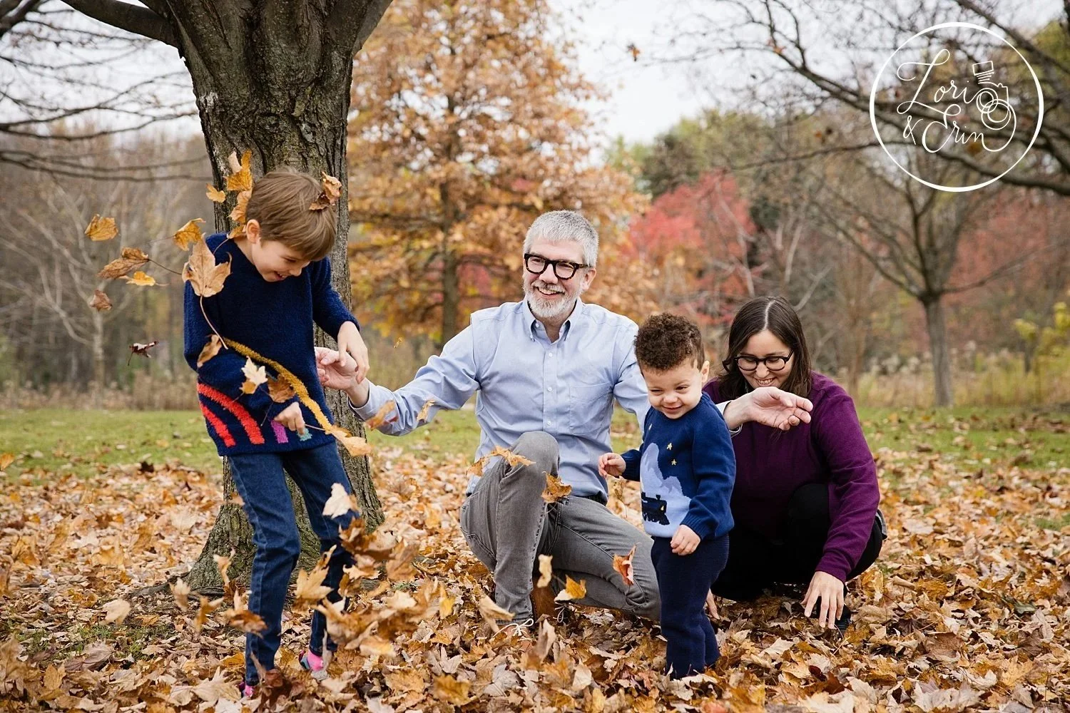 A family portrait session at Tinker Park in the fall where the family is throwing leaves at each other.