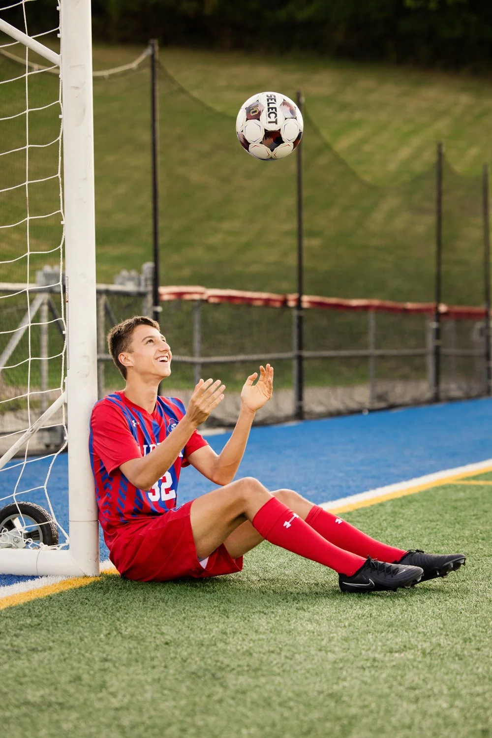 Senior photo session in Fairport NY capturing varsity soccer player near goalpost