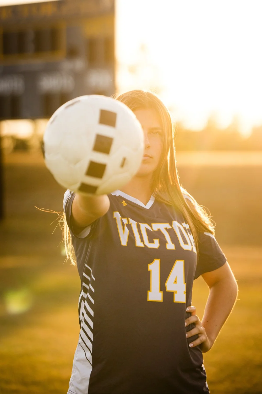 Senior portrait session in Victor NY capturing varsity soccer player in uniform at golden hour