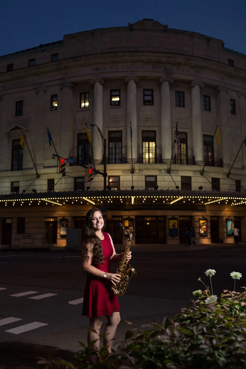 High school senior holding saxophone during senior pictures at Eastman Theatre in Rochester NY at night