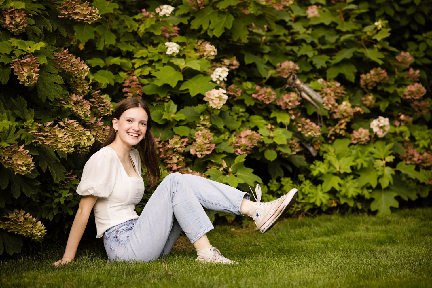 Brighton High School senior pictures featuring senior seated in front of blooming flowers
