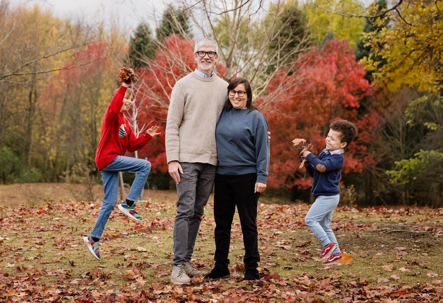Family of four playing in leaves during fall family pictures at Tinker Park