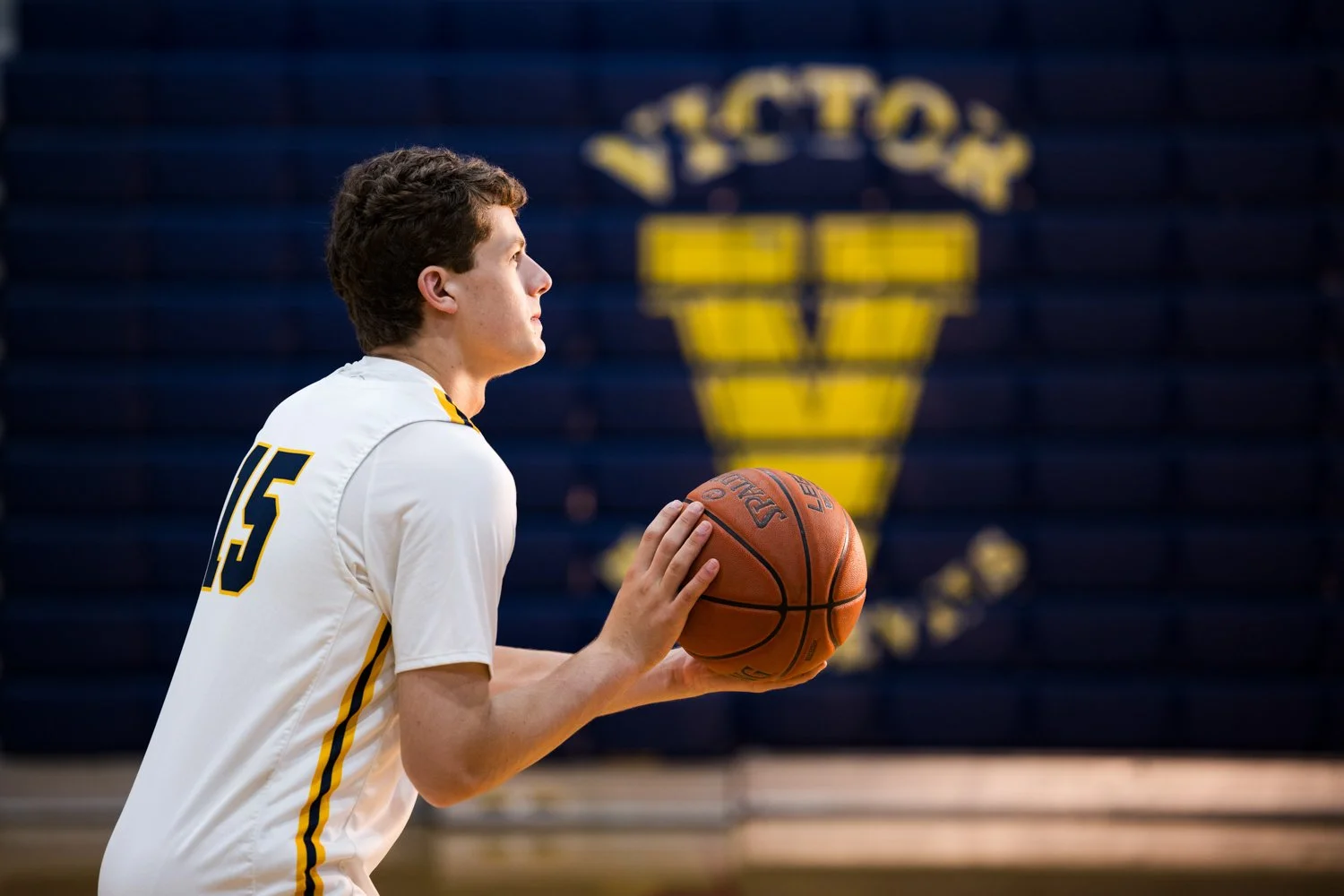Victor NY senior photo session capturing varsity basketball player holding ball ready to shoot