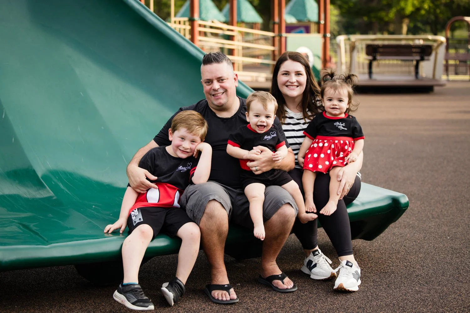 Candid family pictures in Penfield NY featuring family with three kids on playground slide