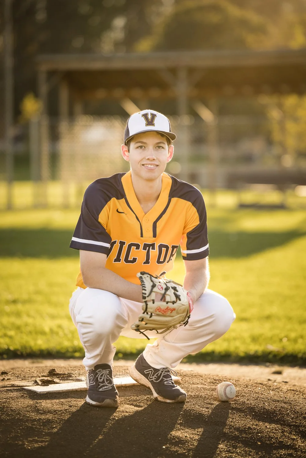 Victor NY senior pictures featuring high school baseball player on pitcher’s mound at sunset