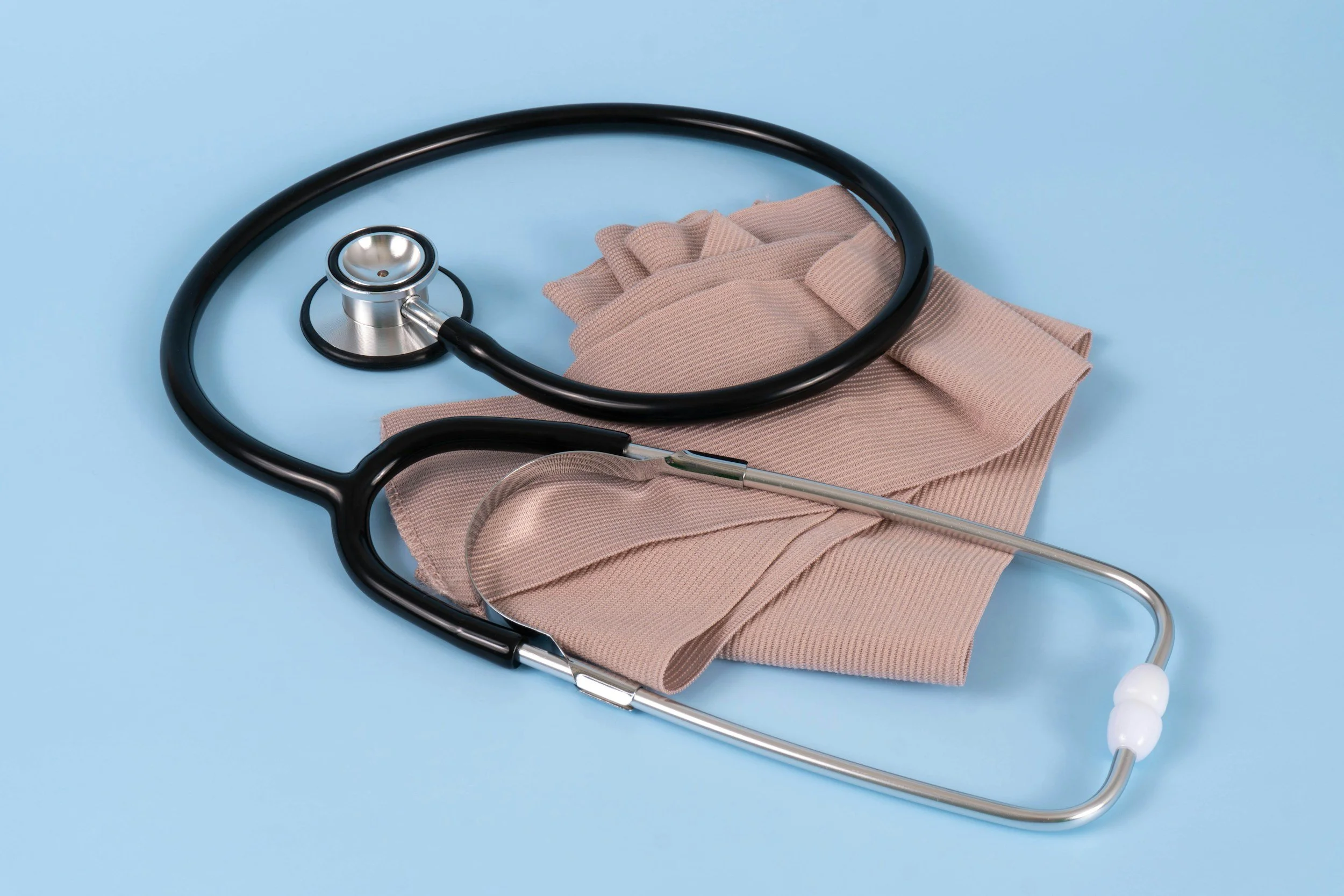 Stethoscope resting on a beige cloth against a light blue background.