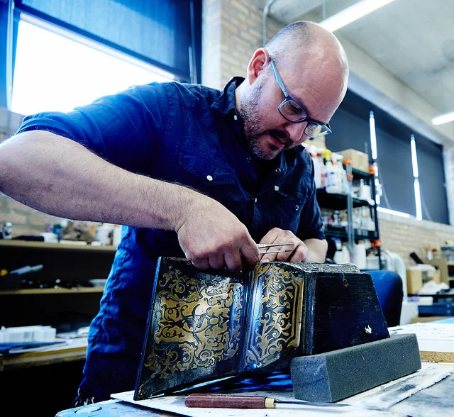 Once all the lost elements are re-cut, the new pieces are puzzle-pieced with the old and all are-reattached to the clock case using reversible adhesives. The brass elements are then polished and the Boullework is covered with a protective layer of wax.