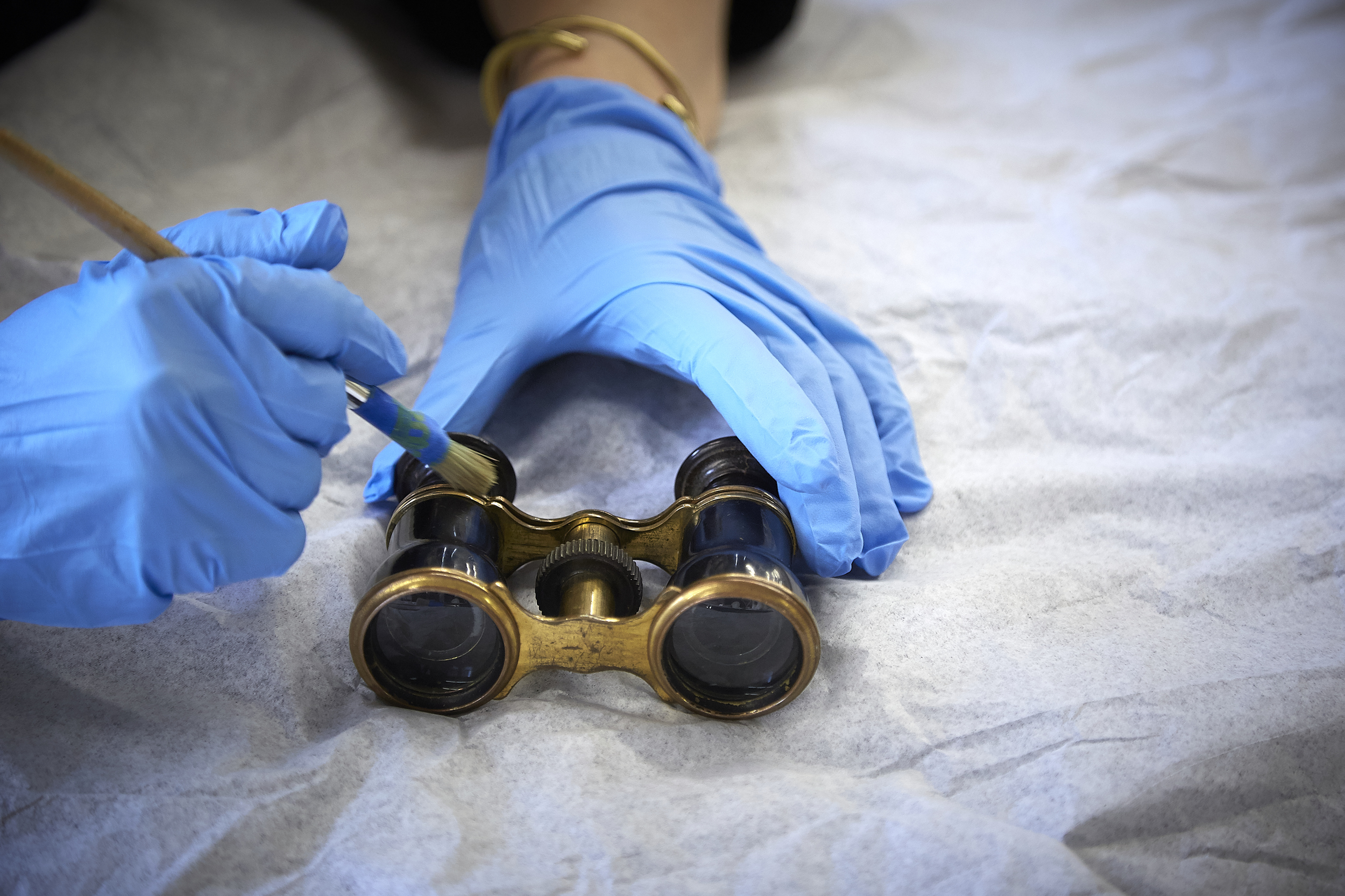 A Conservator working carefully to clean the delicate opera glasses.