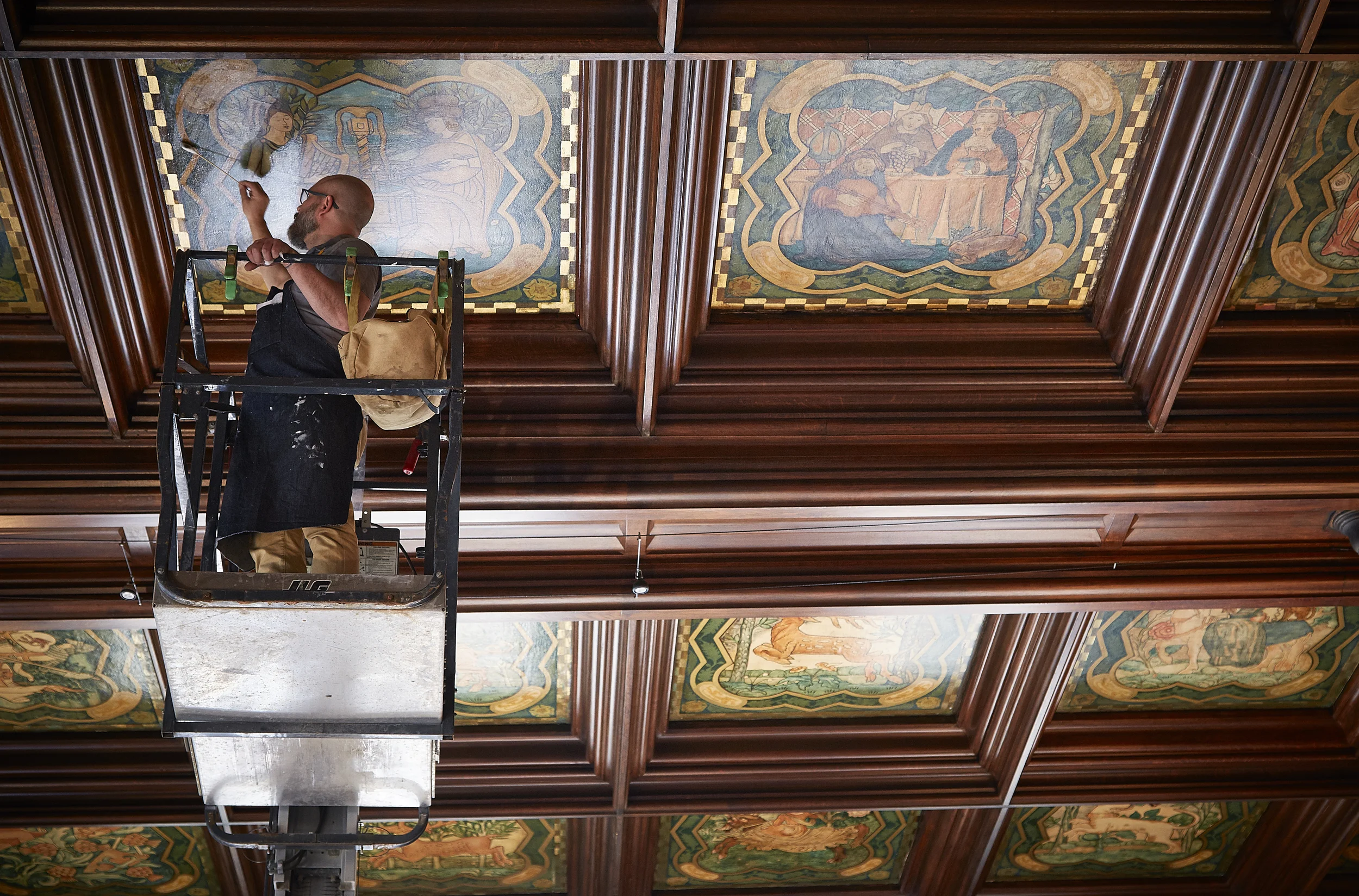 Conservator Andrew Rigby working on one of the ceiling panels in the Michigan Room. 