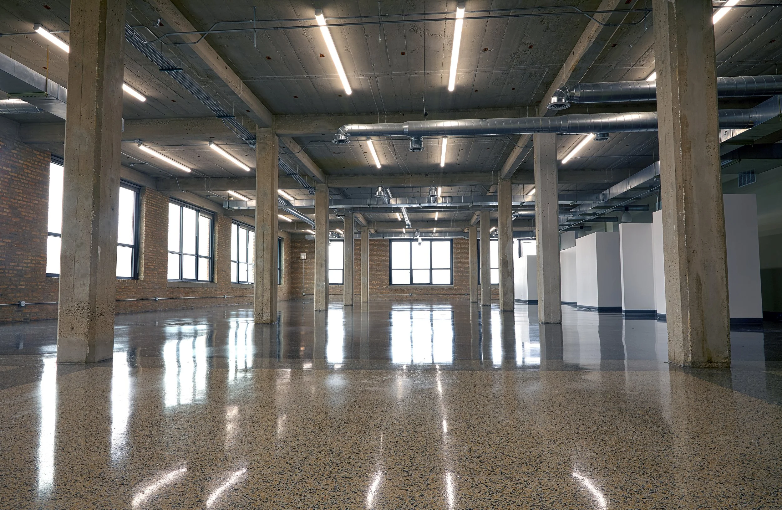 An empty state-of-the-art warehouse with concrete pillars and terrazo flooring.