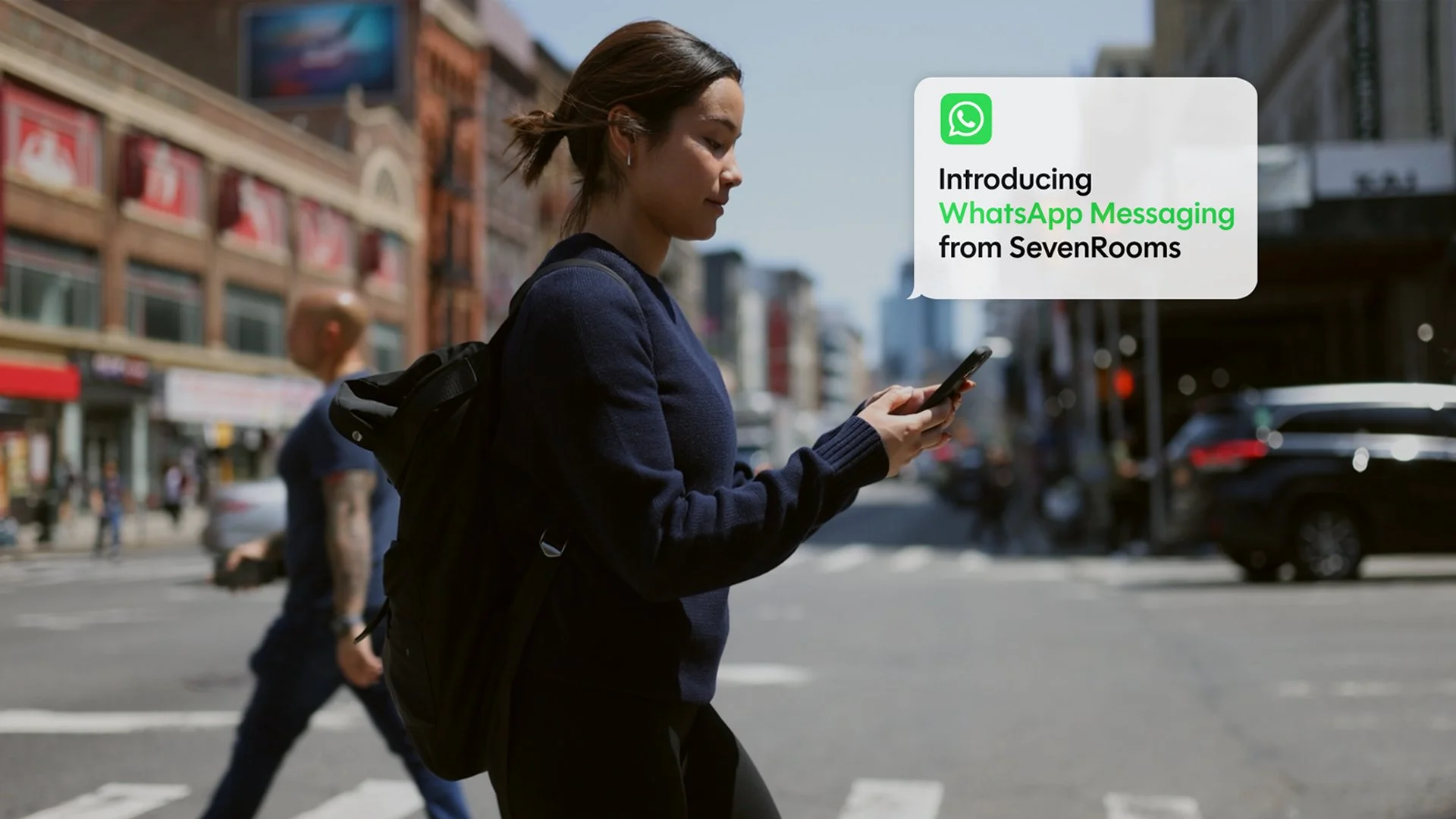 SevenRooms WhatsApp messaging film still, a woman checking a reservation message on her phone on a city street
