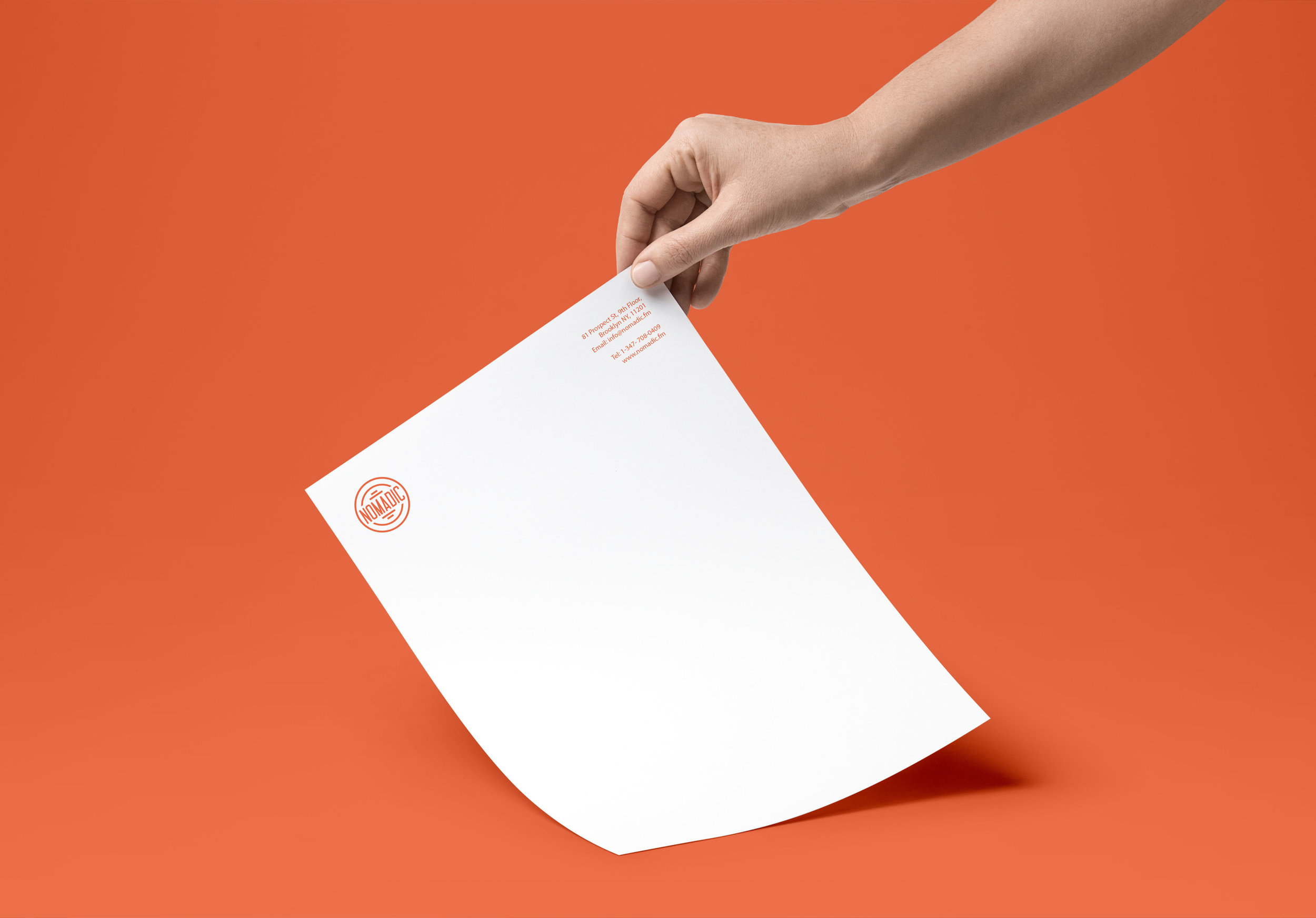 Graphic Designer Leeds A hand holding a Nomadic branded white A4 paper in orange background