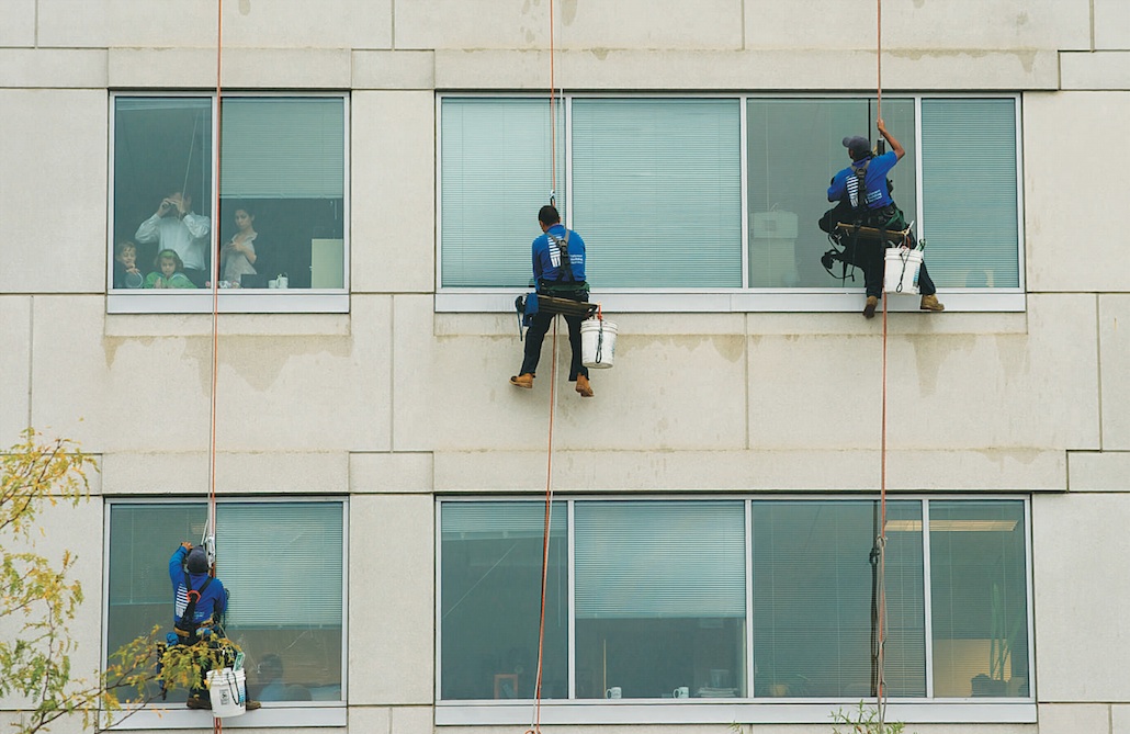   Workers clean a nearby office building as people look out the windows towards the scene of a shooting at the Navy Yard Marine Base in Washington, DC. (Photo by Marlon Correa/The Washington Post)  