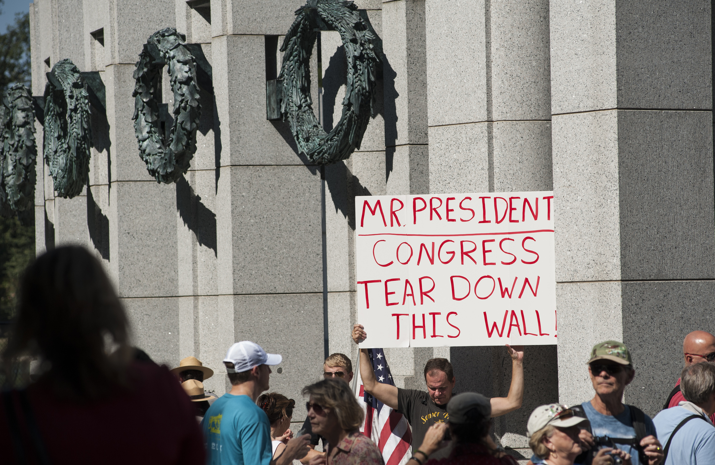A protester holds up a sign that reads "Mr President, Congress, TEAR DOWN THIS WALL" at the WWII Memorial in Washington, DC amid the Government Shutdown.(Photo by Marlon Correa/The Washington Post)