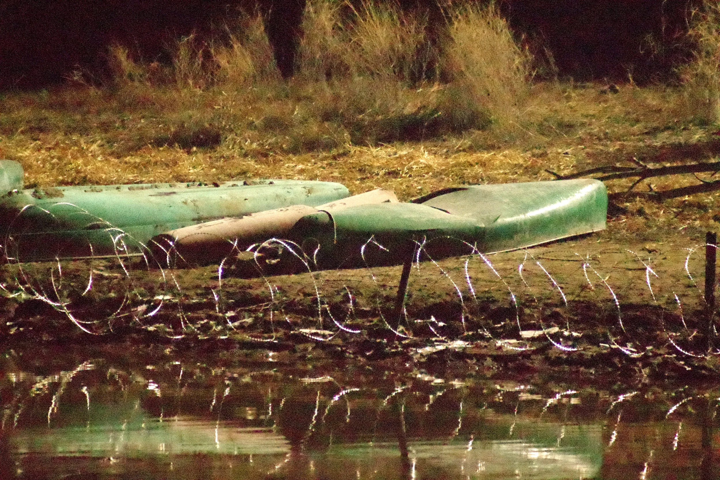 Canoes taken and smashed by cops, and put behind razor wire - at night. Not seen in photo, a beaver swam along the blocked shoreline.