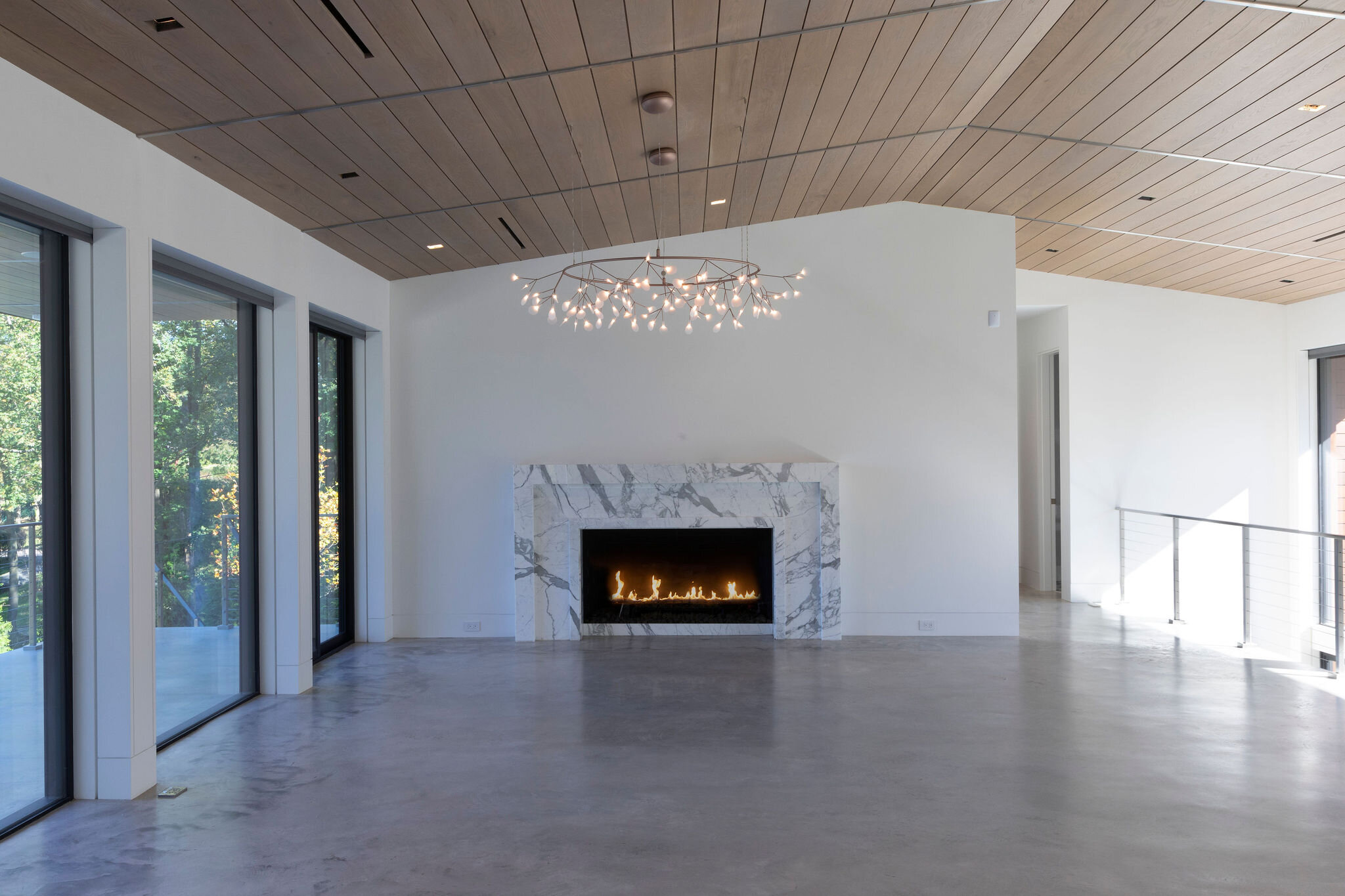  This Arabescato marble fireplace sets the welcoming tone to the living room. The chandelier references the Zen simplicity of the house and the leaves outside. 
