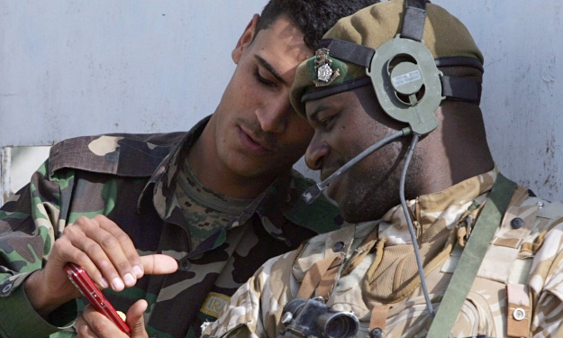 A British soldier looks at an Iraqi colleague's mobile phone during a joint patrol. Photograph: Matt Cardy/Getty Images