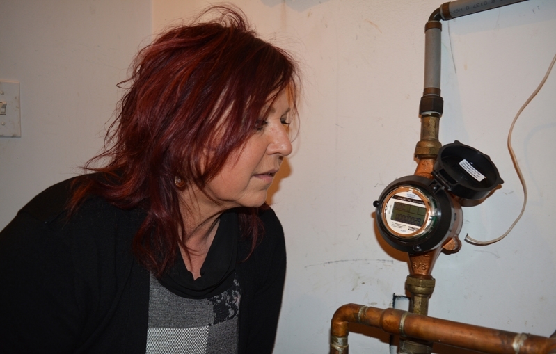 Eva Austin inspects a water meter. The local realtor has heard several complaints about high water bills in recent months and is concerned over water meter issues with the town.