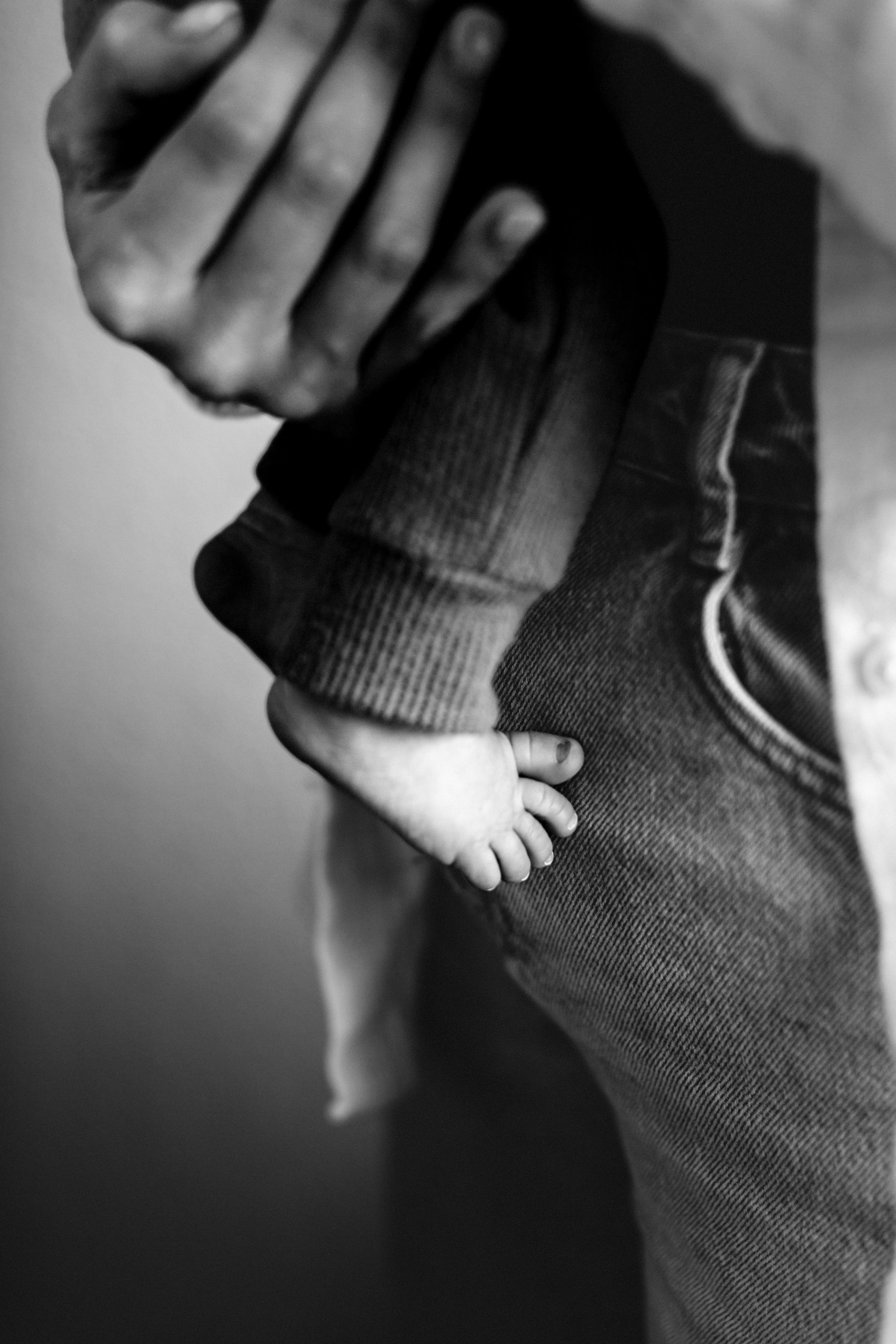 Detail shot of newborn toes during a denver lifestyle newborn session in home with new baby and dog