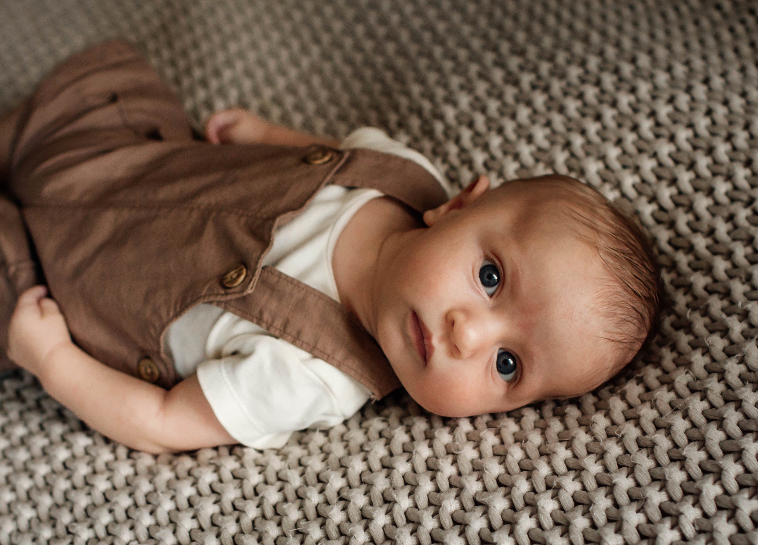 denver newborn lifestyle in home infant photos of solo baby laying on a textured blanket