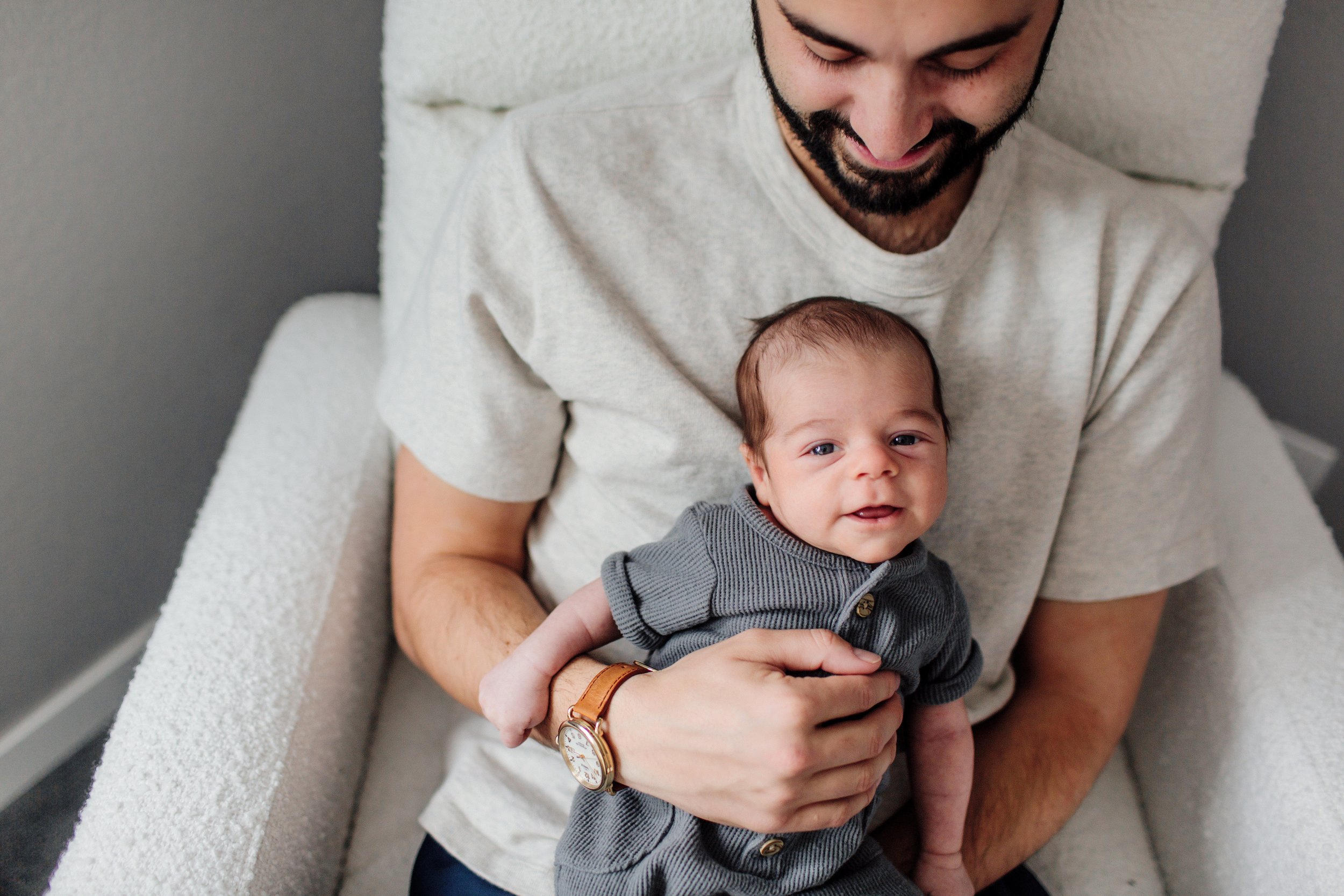 Denver Newborn Lifestyle Portraits in Home infant photos baby in dads lap smiling