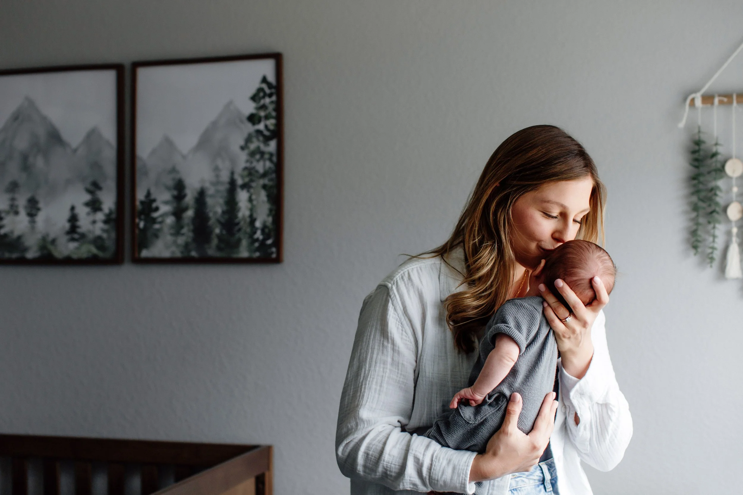mom kissing her newborn in nursery in home for denver baby photo session