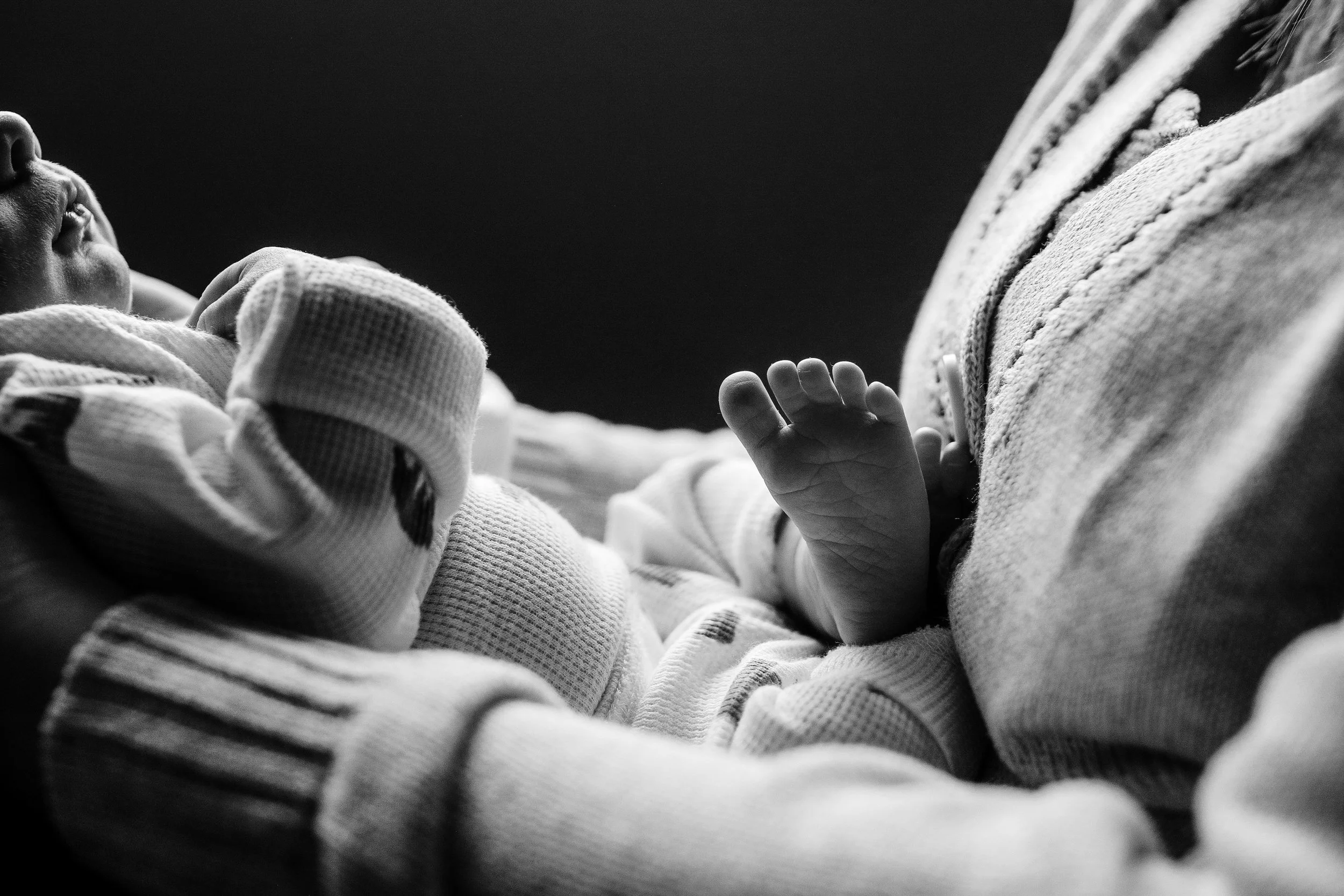 Denver Newborn Lifestyle photos in home with infant and parents detail shot of baby's lips and foot while sitting with mom in the nursery