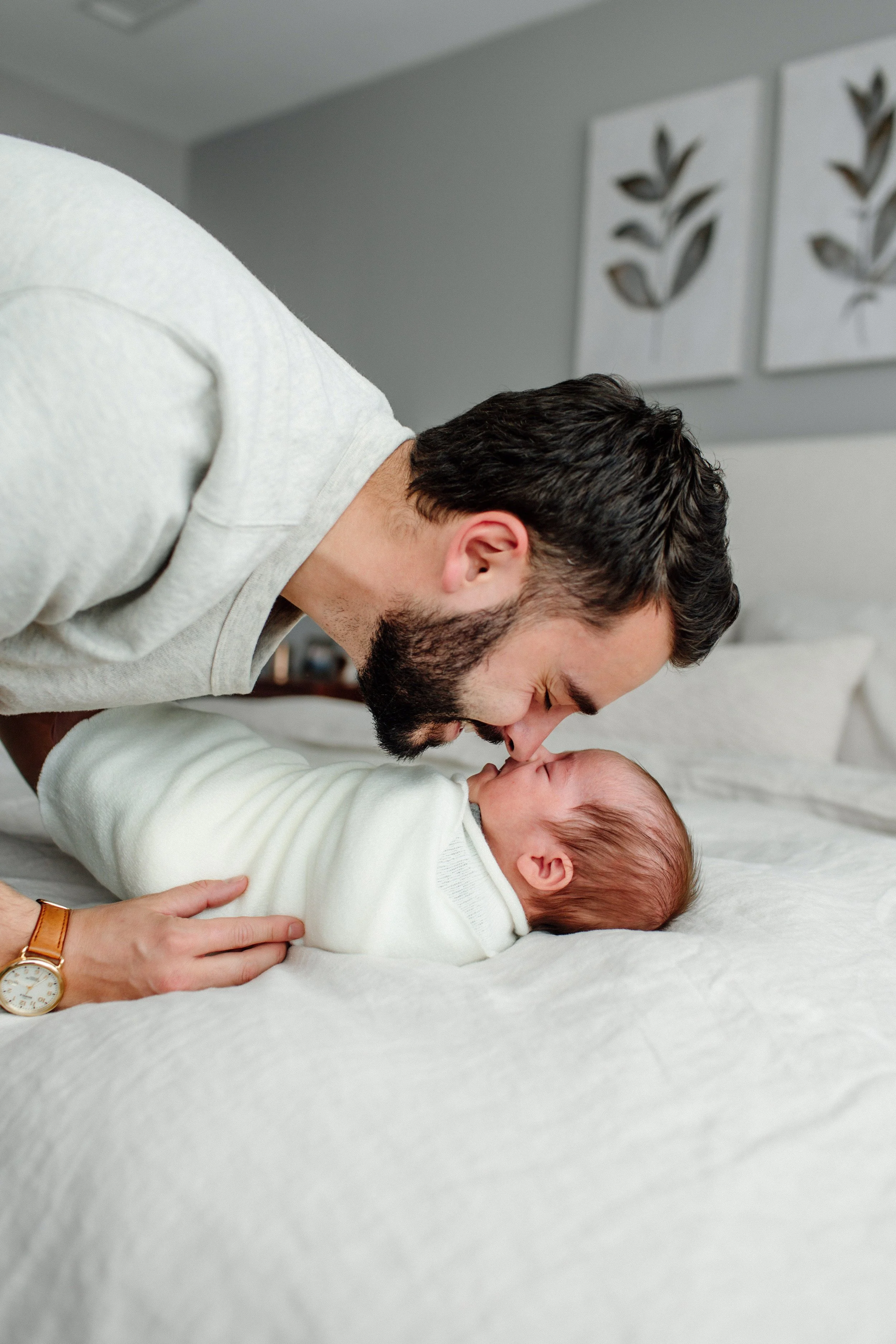 Dad touching nose to nose with newborn baby during lifestyle newborn session in denver while baby lays on bed