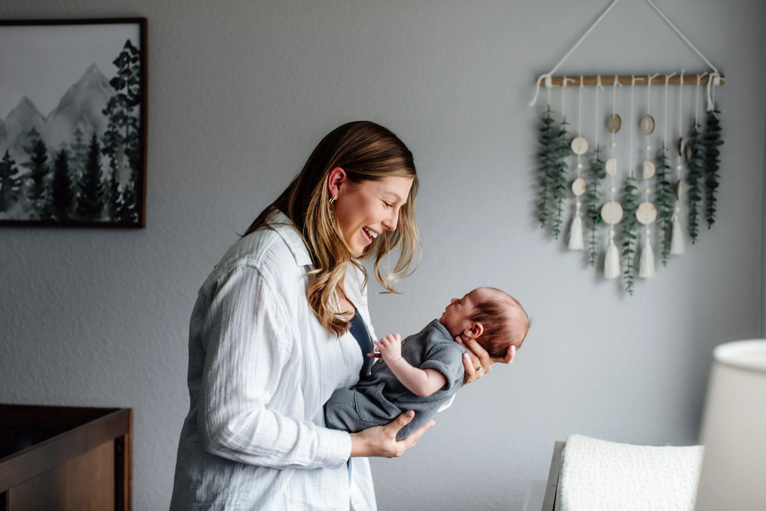 GLowing and excited mom holding her newborn for in home newborn session in Denver
