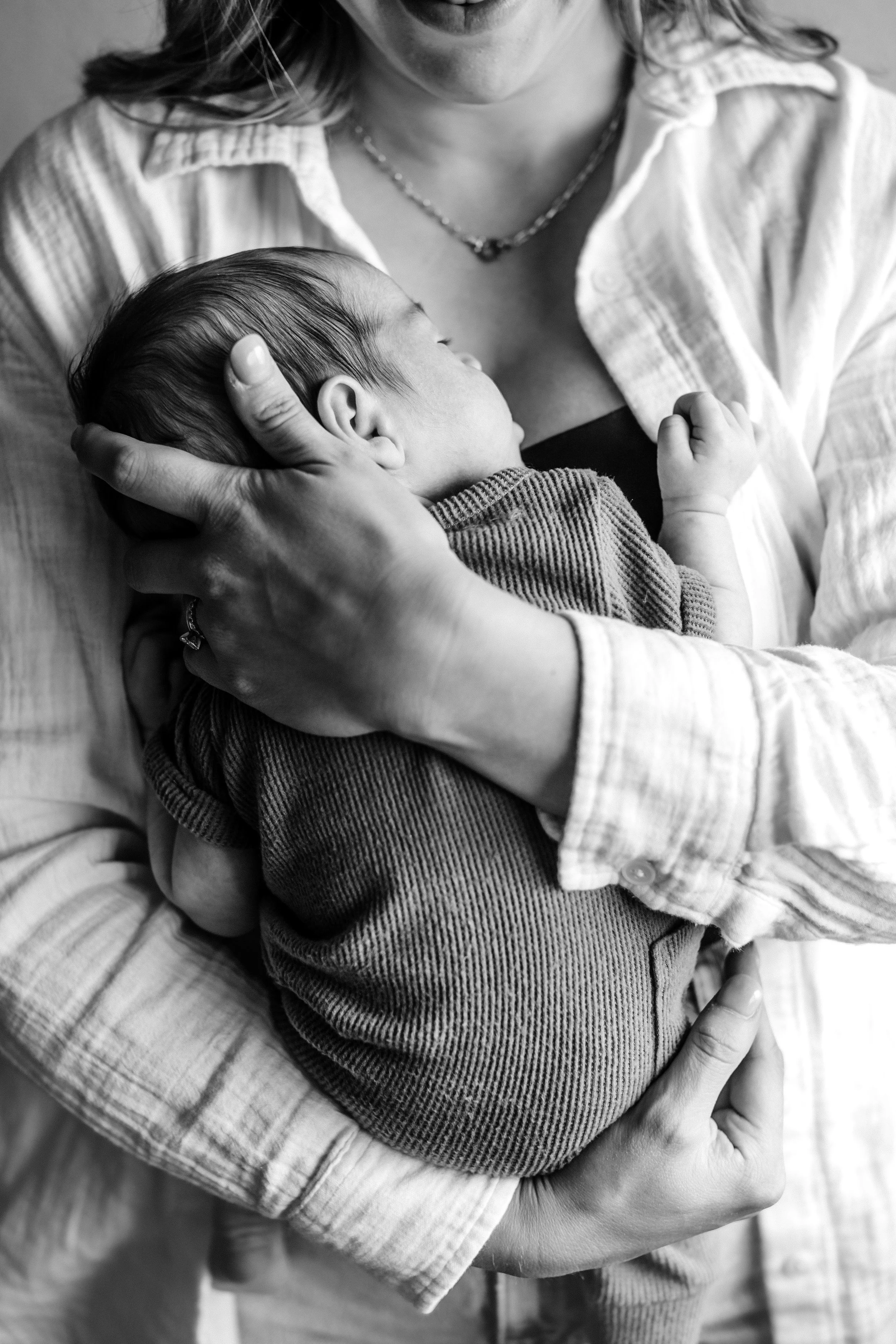 baby snuggled against mom in black and white during a newborn session in home, lifestyle newborn photo session with infant in nursery