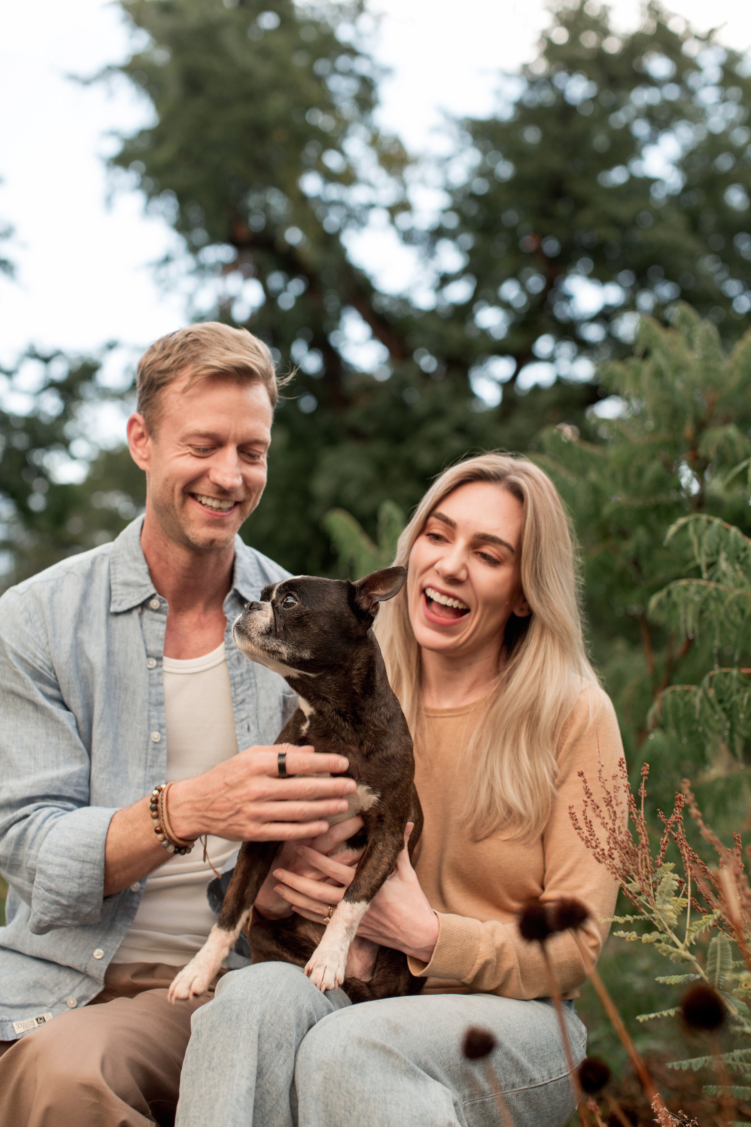 Couple holding their senior Boston Terrier during an outdoor dog photography session in Denver, Colorado.